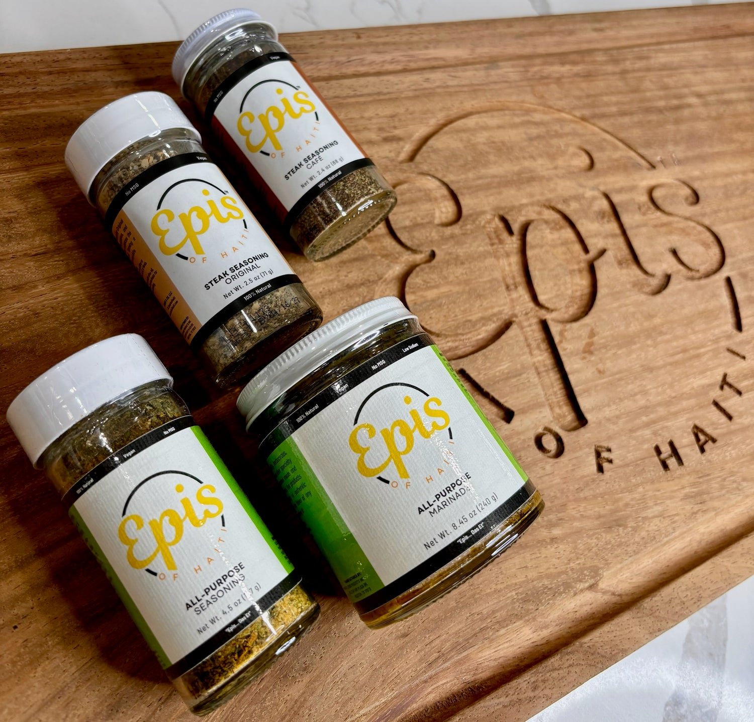 Epis of Haiti seasonings and marinade on a wooden cutting board engraved with the brand logo